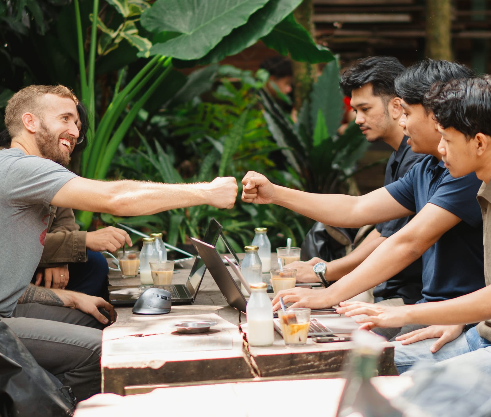 Jon fist bumping a Wawai developer across a table of laptops in Malang